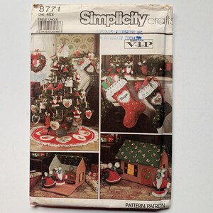Può includere: Un modello di artigianato Simplicity Crafts per realizzare decorazioni natalizie. Il modello include istruzioni per realizzare una gonna per l'albero di Natale, calze e una piccola casa. Il modello è intitolato "Simplicity crafts" e il numero del modello è 8771.