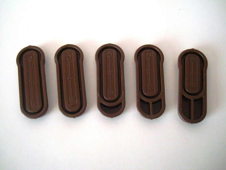 May include: Five brown plastic curtain tiebacks with a textured surface and a small hole at the top. Each tieback has a different measurement printed on it.