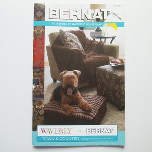Könnte beinhalten: Ein Buchcover mit einem braunen Hund, der auf einem braunen gestrickten Hocker sitzt. Das Buchcover ist für ein Strick- und Häkelmusterbuch namens "Waverly for Bernat Town & Country".