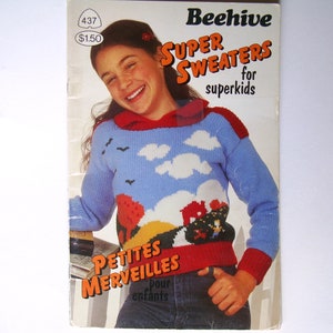 May include: A knitting pattern booklet for children's sweaters. The cover features a girl wearing a blue and red sweater with a colourful design of clouds, birds, and a house. The title of the booklet is "Beehive Super Sweaters for Superkids" and "Petites Merveilles pour enfants".