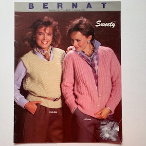 May include: A vintage knitting pattern book from Bernat featuring two women wearing sweaters. The book is titled "Sweety" and has a price of $2.00. The pattern numbers are 1140-544 and 1137-544.