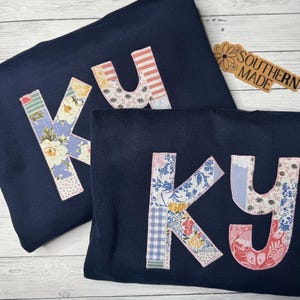 May include: A white ceramic mug with a black handle and the text "But First, Coffee" in a handwritten style. The mug is on a white surface. The mug is approximately 4 inches tall.