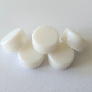 May include: Five white round plastic bottle caps.
