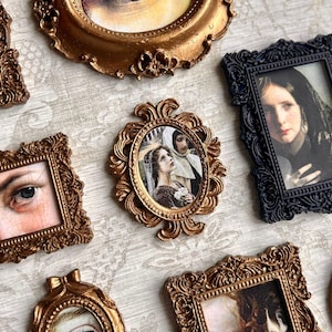Op de afbeelding: Een assortiment sierlijke fotolijsten in antieke stijl. De lijsten zijn voornamelijk goud en zwart, met gedetailleerde gravures. De afbeeldingen in de lijsten tonen portretten en artistieke weergaven, wat een vintage esthetiek creëert.