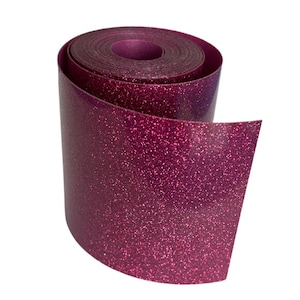 May include: A roll of shimmering, magenta glitter vinyl. The vinyl is tightly rolled, with the end of the roll unfurled, revealing the glittery surface. The material has a smooth, reflective quality, ideal for crafting and decorative projects.