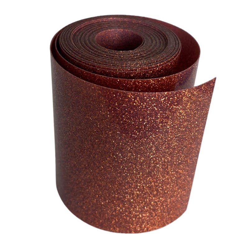 May include: A roll of shimmering, glittery, copper-colored ribbon. The ribbon is tightly rolled, revealing the inner layers and the textured surface of the material. The glitter catches the light, creating a sparkling effect.
