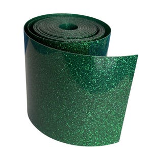 May include: A roll of emerald green glitter ribbon. The ribbon is tightly wound, with the end unfurled, revealing the shiny, textured surface. The glitter catches the light, creating a sparkling effect. Ideal for crafts and decorations.