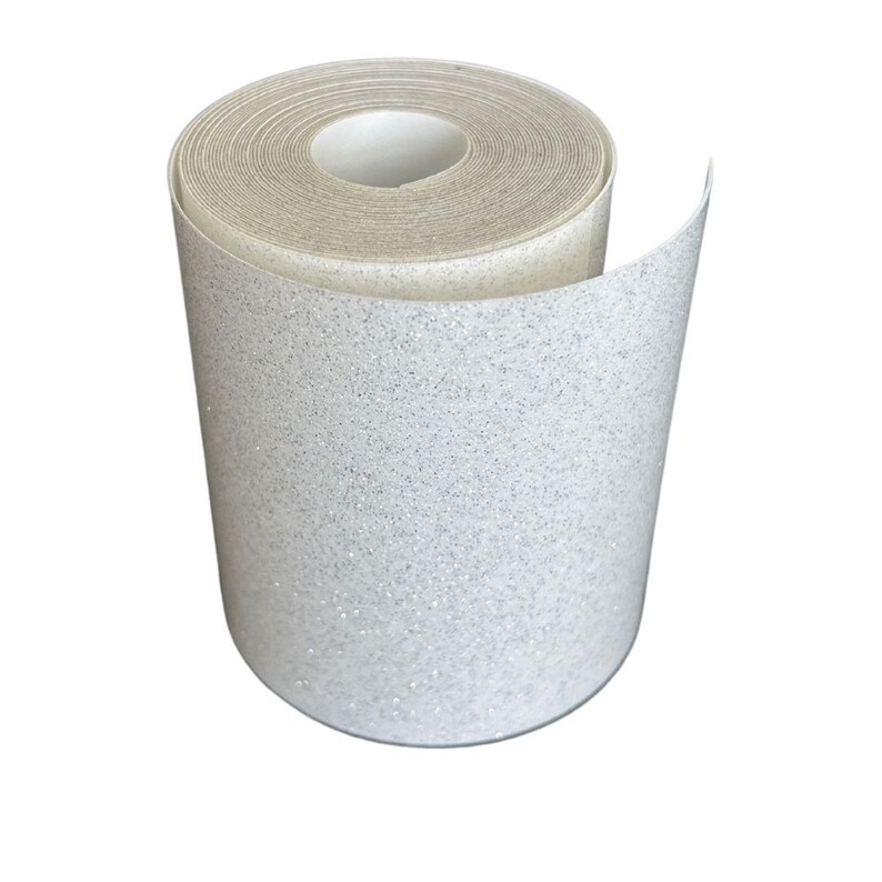 May include: A roll of white glitter wallpaper. The wallpaper is rolled up, revealing the inner core and the outer surface covered in sparkling glitter. The roll is set against a white background.