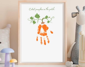May include: A framed print featuring an orange handprint transformed into a pumpkin, with green vines and the text "Cutest pumpkin in the patch." The print is in a light wooden frame, perfect for nursery or fall decor.