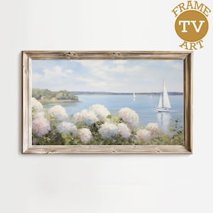 May include: A framed landscape painting depicts a serene coastal scene. White sailboats glide on a blue body of water, with white and pink hydrangeas in the foreground. The artwork is framed in a light brown, rustic-style frame. The text "FRAME TV ART" is in the upper right corner.