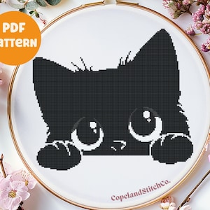 May include: Black and white cross stitch pattern of a cat peeking over the edge of a hoop. The cat has large eyes and a cute expression.
