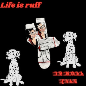 May include: A pair of white socks with a cartoon image of Cruella De Vil from Disney's 101 Dalmatians. The socks have a red and white striped cuff and the text "Life is Ruff" is written in red at the top of the image. Two Dalmatian puppies are also pictured in the image.
