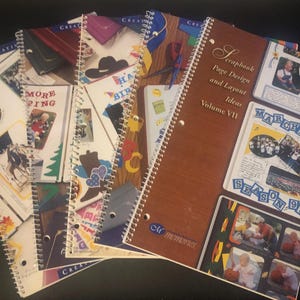 May include: A stack of spiral-bound scrapbooking idea books. The covers feature various designs, including a cowboy hat, a purse, and the text "MORE PING." One book reads "Scrapbook Page Design and Layout Ideas Volume VII."