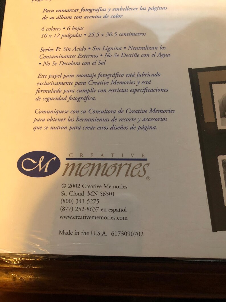 May include: A close-up of a product packaging for Creative Memories photo albums. The packaging is white with blue and black text. The text reads "Creative Memories" and includes the company's website and phone number. The packaging also includes the text "Made in the U.S.A. 6173090702".
