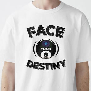 Peut inclure: T-shirt blanc avec l'inscription noire "FACE YOUR DESTINY", entourant un graphisme de boule de billard noire et blanche. Le graphisme de la boule de billard porte le mot "YOUR" au-dessus du chiffre 8.