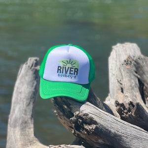 May include: Green and white trucker hat with a sun and the text "River Vibes" on the front.