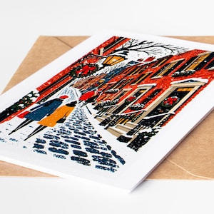 Boston Christmas card lying on a kraft envelope, folk art Beacon Hill gas lamps and brick row houses under snow