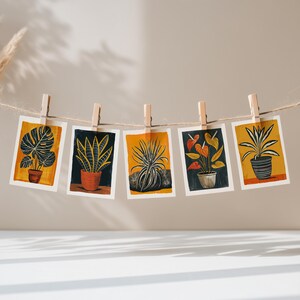 Five houseplant greeting cards pegged on a string in warm daylight