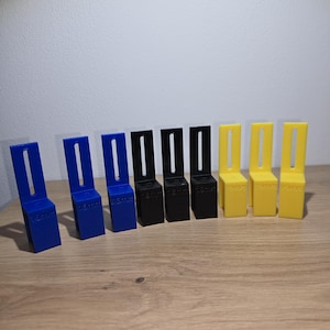 Könnte beinhalten: Ein Satz mit 10 Abstandshaltern aus Kunststoff in drei Farben: Blau, Schwarz und Gelb. Jeder Abstandshalter hat eine andere, aufgedruckte Maßeinheit, die von 15 mm bis 19 mm reicht.
