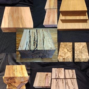 May include: A collection of various wooden blocks, showcasing unique grain patterns and colors. The blocks are rectangular and square, with natural wood tones ranging from light beige to dark brown, and some with black streaks.