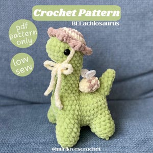 Könnte beinhalten: Häkelanleitung für einen grünen Dinosaurier, der einen rosa-weißen Hut mit einer Biene auf dem Rücken trägt. Das Muster ist als PDF-Download verfügbar und ist mit wenig Nähen versehen. Der Text "BEEachiosaurus" ist im Bild sichtbar.