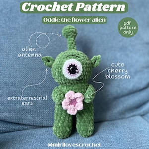 May include: Crochet pattern for a green alien with a single large eye, holding a pink flower. The alien has a long antenna and large ears. The text "Oddie the flower alien" and "pdf pattern only" is visible in the image.