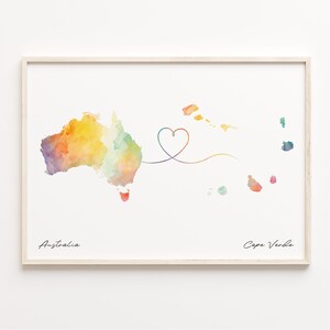 Peut inclure: Une impression de carte aquarelle avec une ligne en forme de cœur reliant l'Australie et le Cap-Vert. La carte est peinte dans des tons de jaune, orange, vert et bleu.