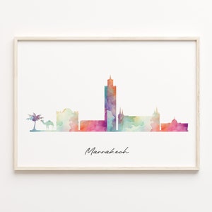 May include: A watercolour painting of the Marrakech skyline, featuring a tall minaret and other buildings in shades of pink, purple, blue, and green. The painting includes a camel and a palm tree in the foreground. The text "Marrakech" is written in cursive at the bottom of the painting.