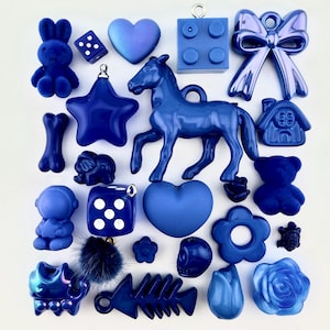 May include: An assortment of blue charms and embellishments. The collection includes a bunny, dice, hearts, a building block, a bow, a star, a horse, a house, a teddy bear, a skull, a flower, a fish bone, a turtle, a rose, and a tulip. Ideal for crafting.