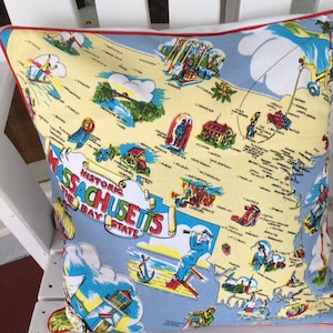 May include: A blue and yellow throw pillow with a map of Massachusetts on it. The map is labeled "Historic Massachusetts, The Bay State".