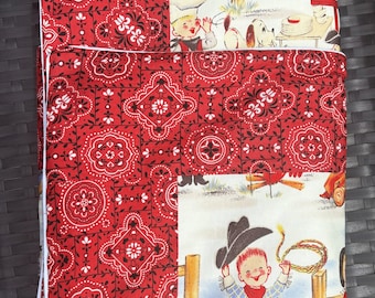 May include: Red and white bandana print fabric with a white background featuring a cowboy scene with two cowboys and a dog. The cowboys are wearing blue jeans and red and white shirts. One cowboy is holding a lasso.