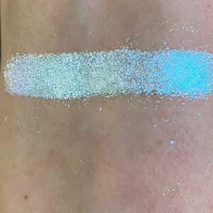 May include: A close-up of a white iridescent glitter, showing its shimmery texture and subtle blue and purple hues.