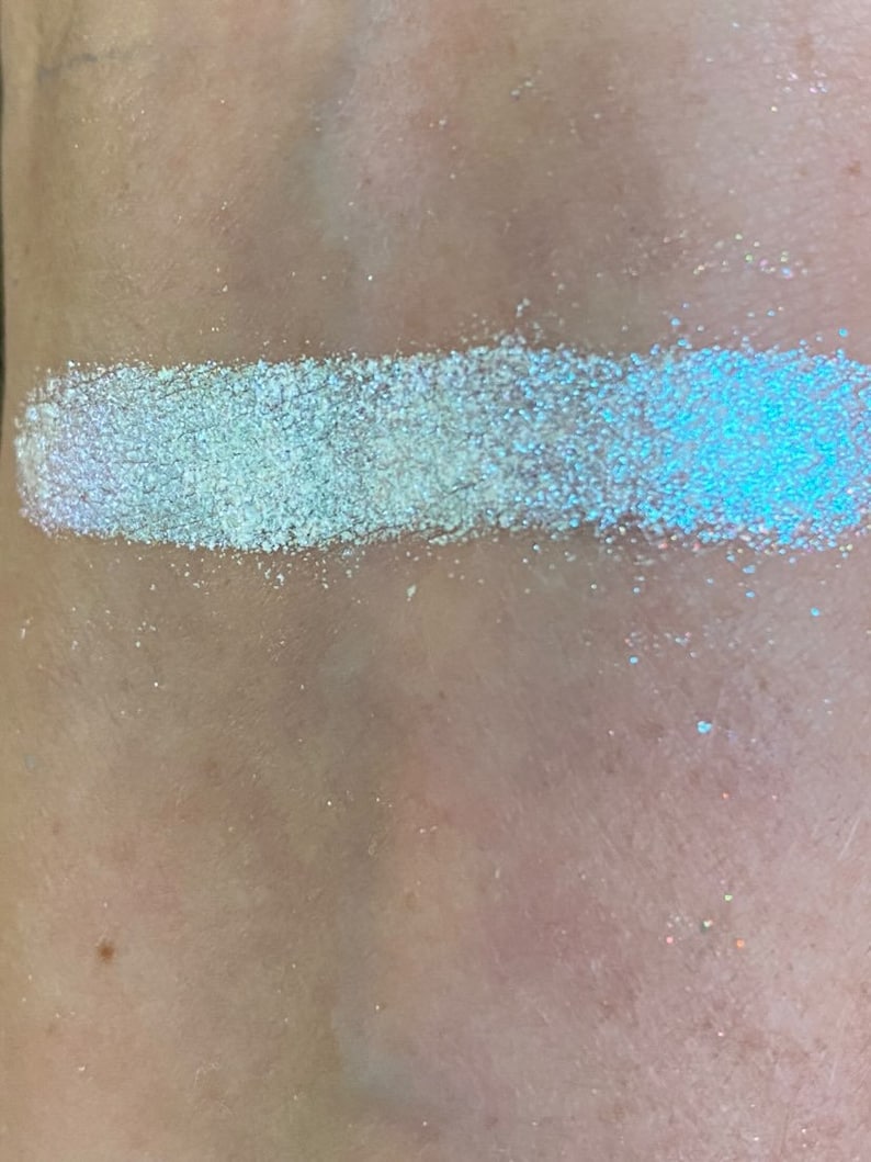 May include: A close-up of a white iridescent glitter, showing its shimmery texture and subtle blue and purple hues.