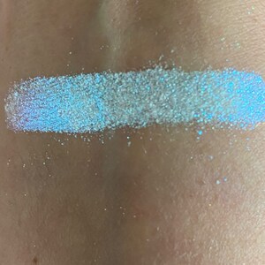 May include: A close-up of a white iridescent glitter, showing its shimmery texture and blue undertones.
