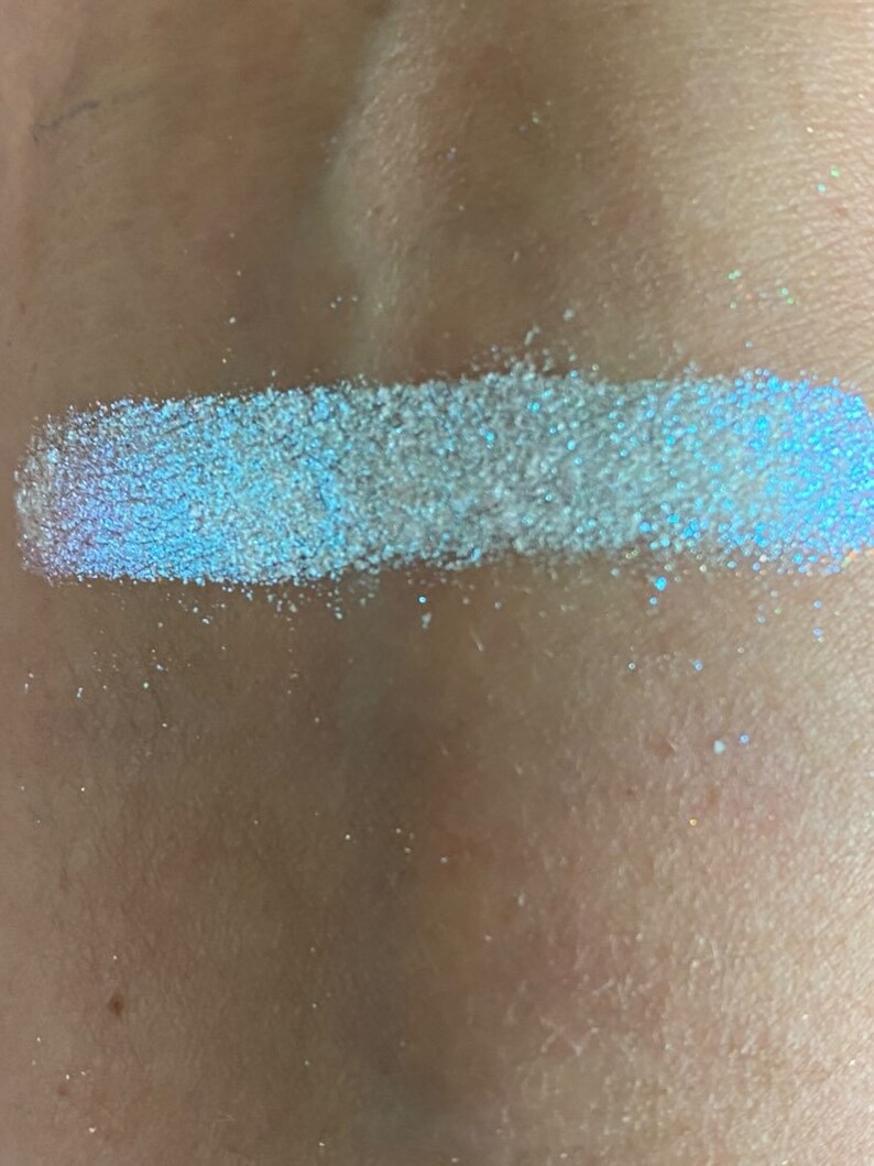 May include: A close-up of a white iridescent glitter, showing its shimmery texture and blue undertones.