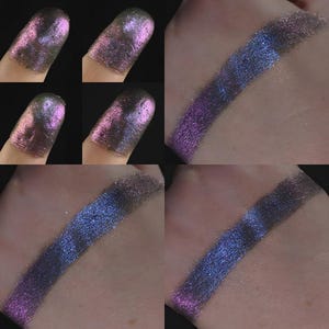Peut inclure: Gros plan sur des échantillons de fard à paupières dans différentes nuances de violet, de bleu et d'argent. Le fard à paupières est appliqué sur le bout des doigts et sur une main, mettant en valeur le rendu des couleurs et les reflets.