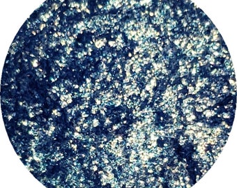 May include: A round, blue eyeshadow with a shimmery finish. The eyeshadow is made of finely milled powder and has a smooth, silky texture.