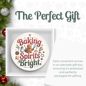 May include: A round, white Christmas ornament with the text "Baking Spirits Bright" in red and green. The ornament features illustrations of baking tools and a gingerbread man. The ornament is presented in a white gift box.