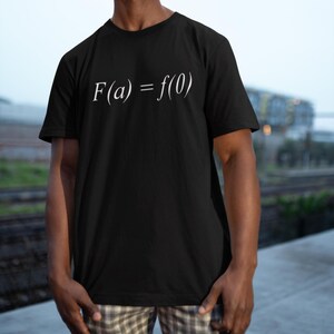 Puede incluir: Camiseta negra con la ecuación matemática "F(a) = f(0)" impresa en blanco. La camiseta tiene cuello redondo y parece estar hecha de un material suave.