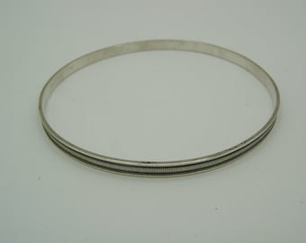 Könnte beinhalten: Ein silbernes Armreif-Armband mit einer strukturierten Blende.
