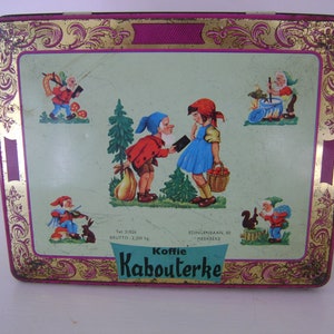May include: A vintage tin box with a green background and gold trim. The box features illustrations of gnomes and a girl in a red dress. The text on the box reads "Koffie Kabouterke" and includes the address "Edingenbaan, 80 - Meerbeke".