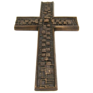 Puede incluir: Cruz de color bronce con un diseño geométrico texturizado. La cruz tiene forma rectangular con un patrón detallado de cuadrados y líneas en su superficie. La cruz está sobre un fondo blanco.