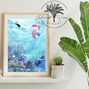 May include: A watercolor painting of an underwater scene with a diver, jellyfish, coral, and fish. The painting is framed in a light wood frame.