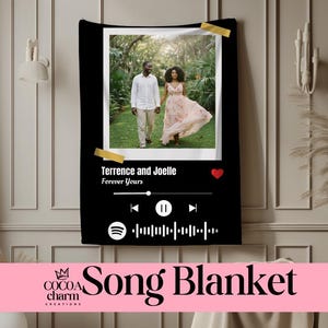 May include: Black song blanket featuring a photo of a couple walking in a park. The blanket has a music player interface design with the text "Terrence and Joelle Forever Yours". The blanket also has the words "Song Blanket" and the Cocoa Charm Creations logo.