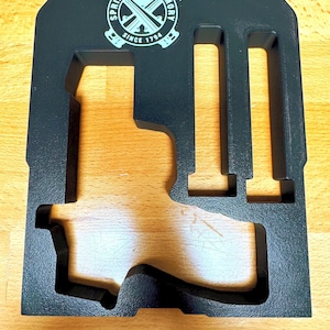 May include: Black gun case with cutouts for a handgun and magazines. The case has the text "SPRINGFIELD ARMORY" and "SINCE 1794" in a circular logo.
