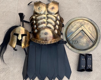 May include: A complete set of antique-style Spartan armor, including a brass breastplate, helmet with a black plume, shield, greaves, and a black leather skirt. The armor is displayed on a light-colored surface.