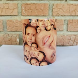 Op de afbeelding: Een cilindrische mok met een herhaald patroon van gezichten. De gezichten zijn van dezelfde persoon en bedekken het hele oppervlak van de mok. De binnenkant van de mok is wit en heeft een glanzende afwerking.