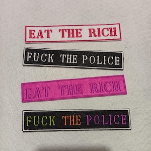 Peut inclure: Quatre écussons rectangulaires brodés avec du texte. Deux écussons lisent "EAT THE RICH" en fil rouge sur fond blanc et rose. Les deux autres écussons lisent "FUCK THE POLICE" en fil blanc et orange sur fond noir.
