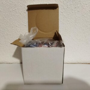 May include: A white cardboard box with a brown lid. The box is open and filled with clear plastic packing material.