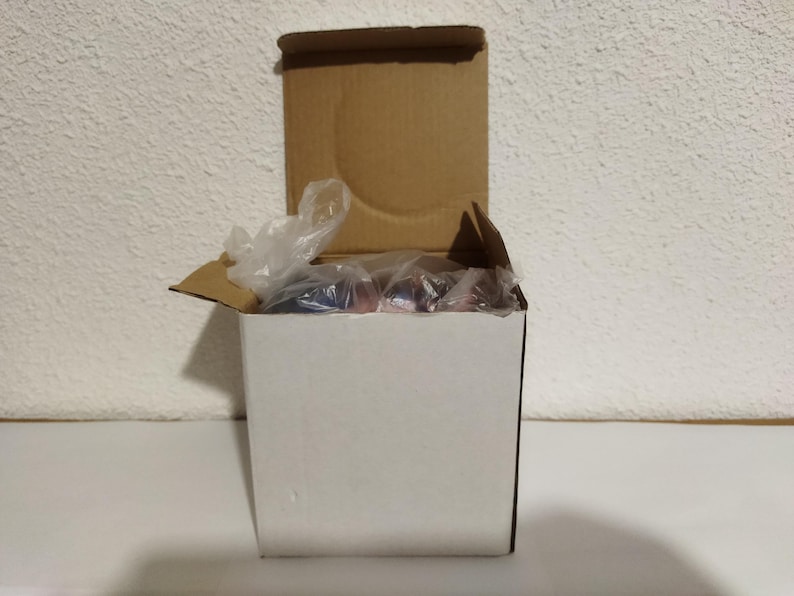 May include: A white cardboard box with a brown lid. The box is open and filled with clear plastic packing material.